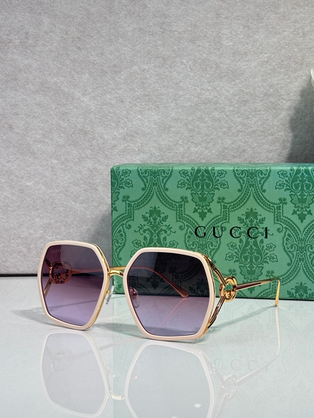 Sunglasses with rose-pink square frames and mauve tinted lenses, gold-tone accents