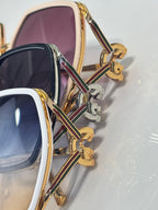 Sunglasses close-up: gold-tone temples with multicolor stripe detail and logo hinge