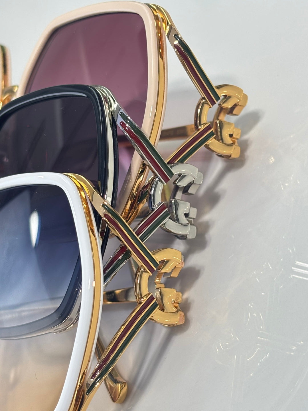 Sunglasses close-up: gold-tone temples with multicolor stripe detail and logo hinge
