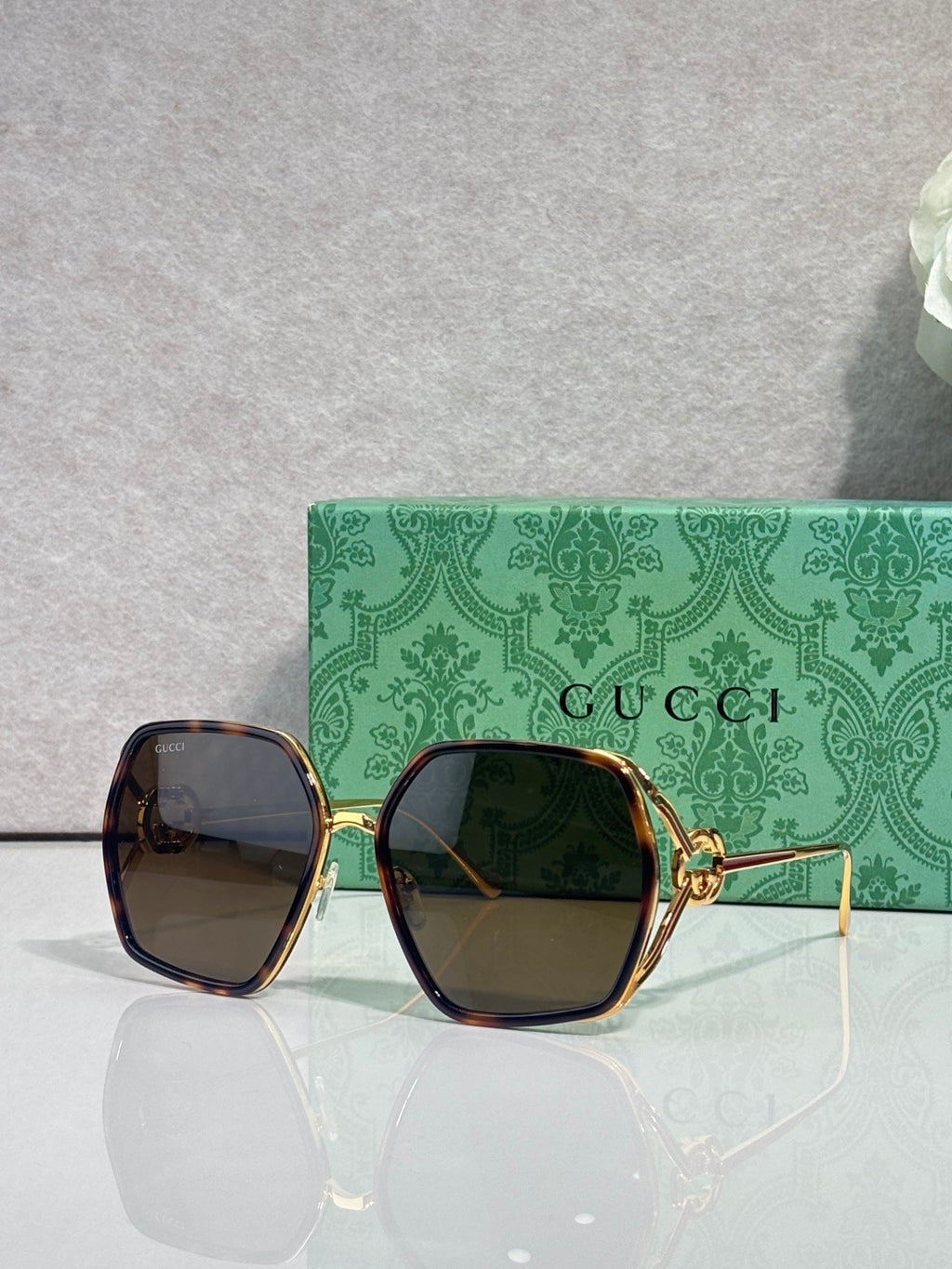Sunglasses with dark maroon square frames and blue tinted lenses, gold-tone accents