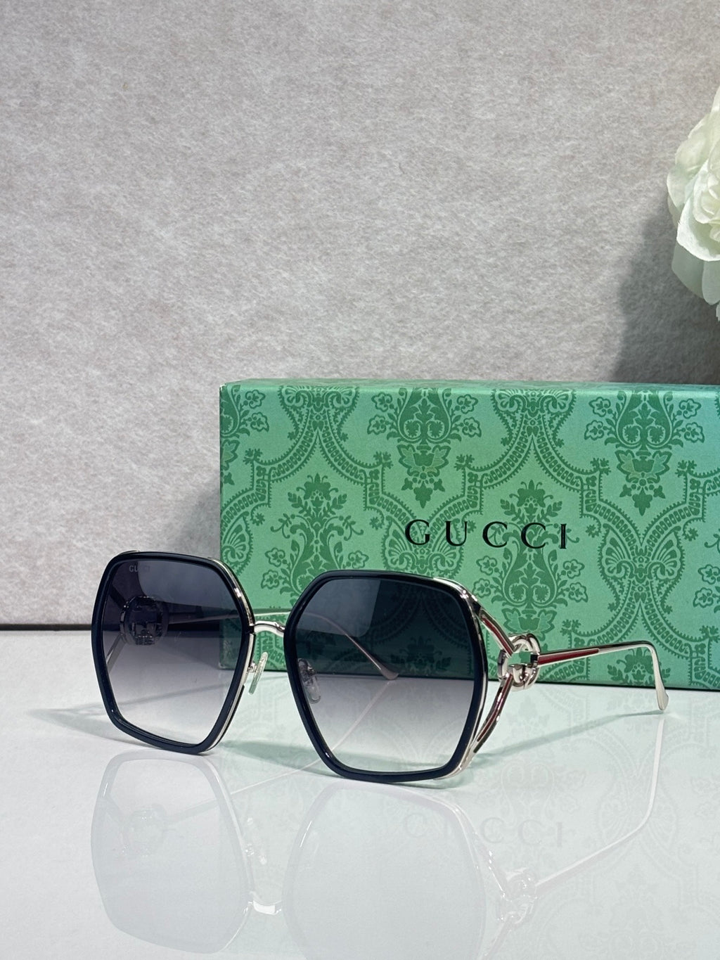 Sunglasses with dark navy square frames, smoky blue lenses, and gold-tone hardware