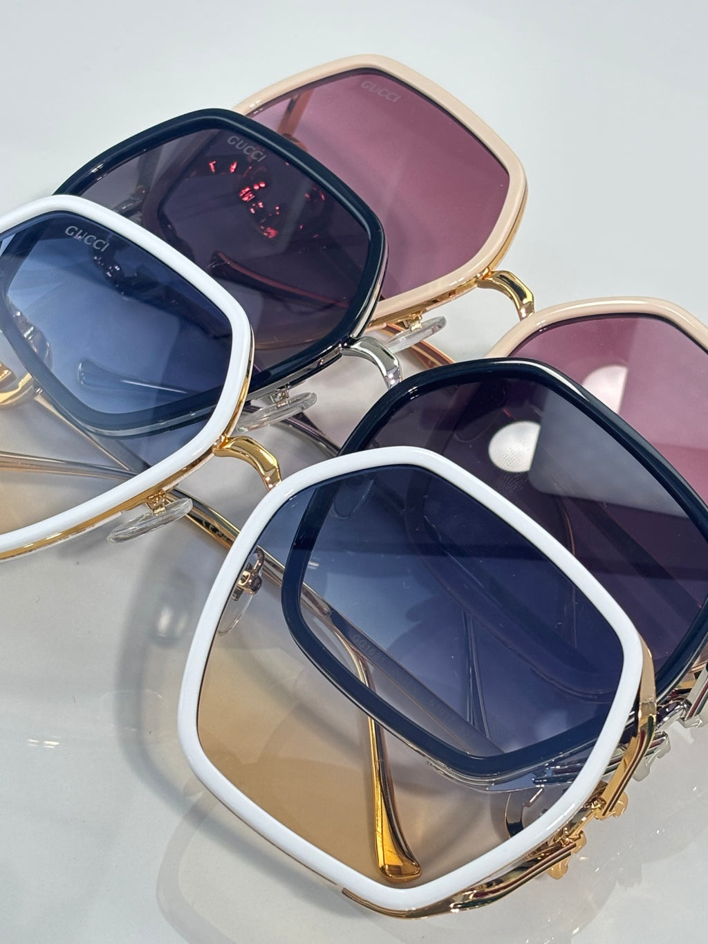 Sunglasses with white and gold square frames, navy lenses, and pink lens backing