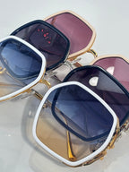 Sunglasses with white and gold square frames, navy lenses, and pink lens backing