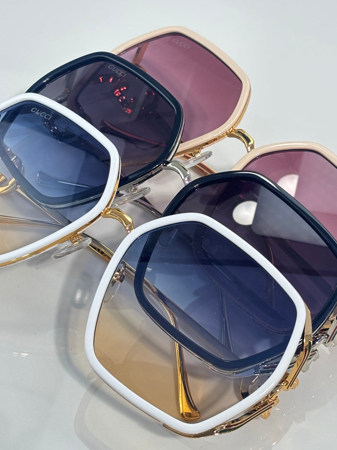 Sunglasses with white and gold square frames, navy lenses, and pink lens backing