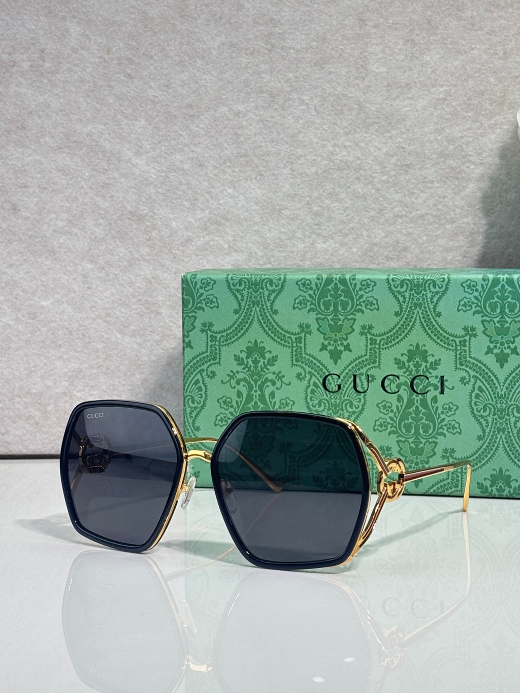 Sunglasses with dark navy square frames, blue lenses, and gold-tone metal hinges