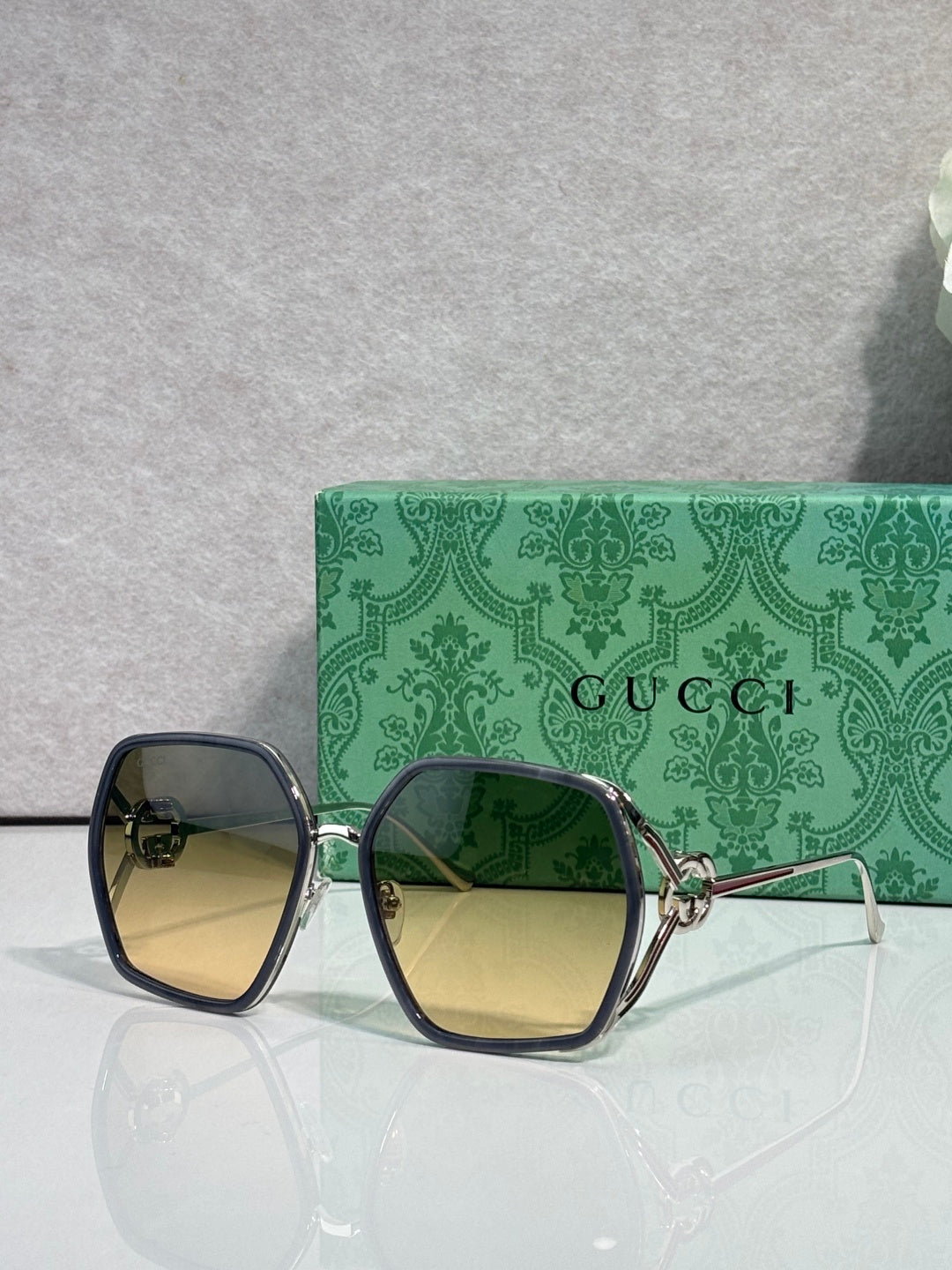 Sunglasses with dark navy square frames and blue gradient lenses, gold-tone details