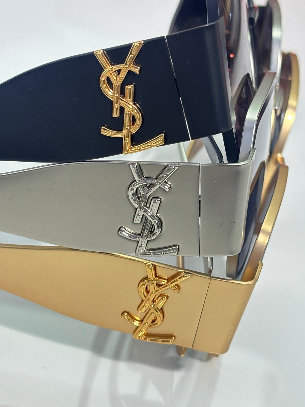 Sunglasses temples with YSL logo plaques in navy, silver, and gold