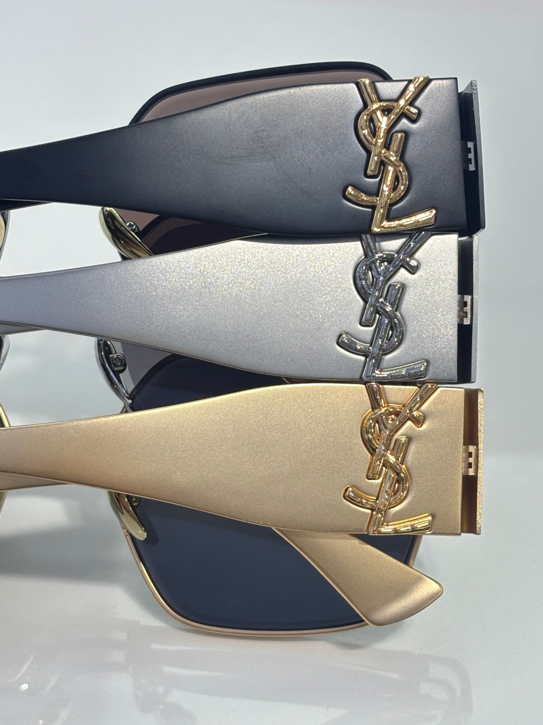 Sunglasses temples with YSL logo plaques in navy, silver, and champagne gold