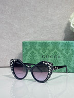 Gucci glasses with dark navy cat-eye frames, rhinestone star trim, dark lenses.