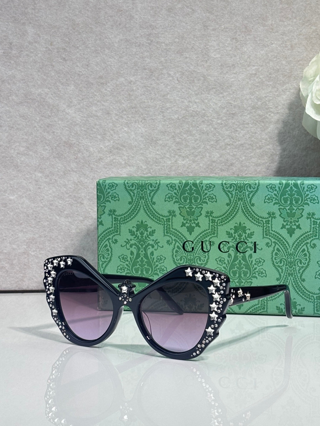 Gucci glasses with dark navy cat-eye frames, rhinestone star trim, dark lenses.