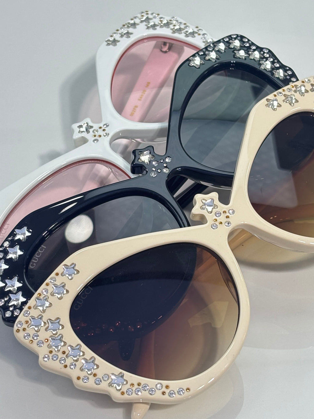 Gucci glasses with assorted cream, black, and white cat-eye frames, rhinestone stars.