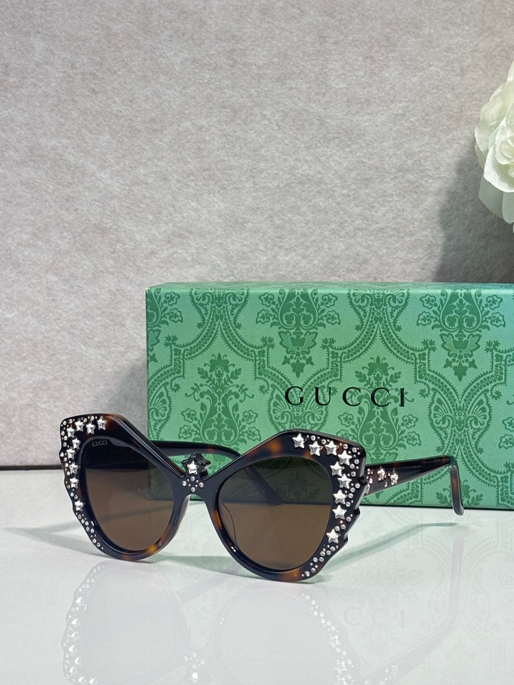 Gucci glasses with black cat-eye frames, rhinestone star trim, dark lenses.