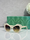 Gucci glasses with white cat-eye frames, rhinestone star accents, dark lenses.