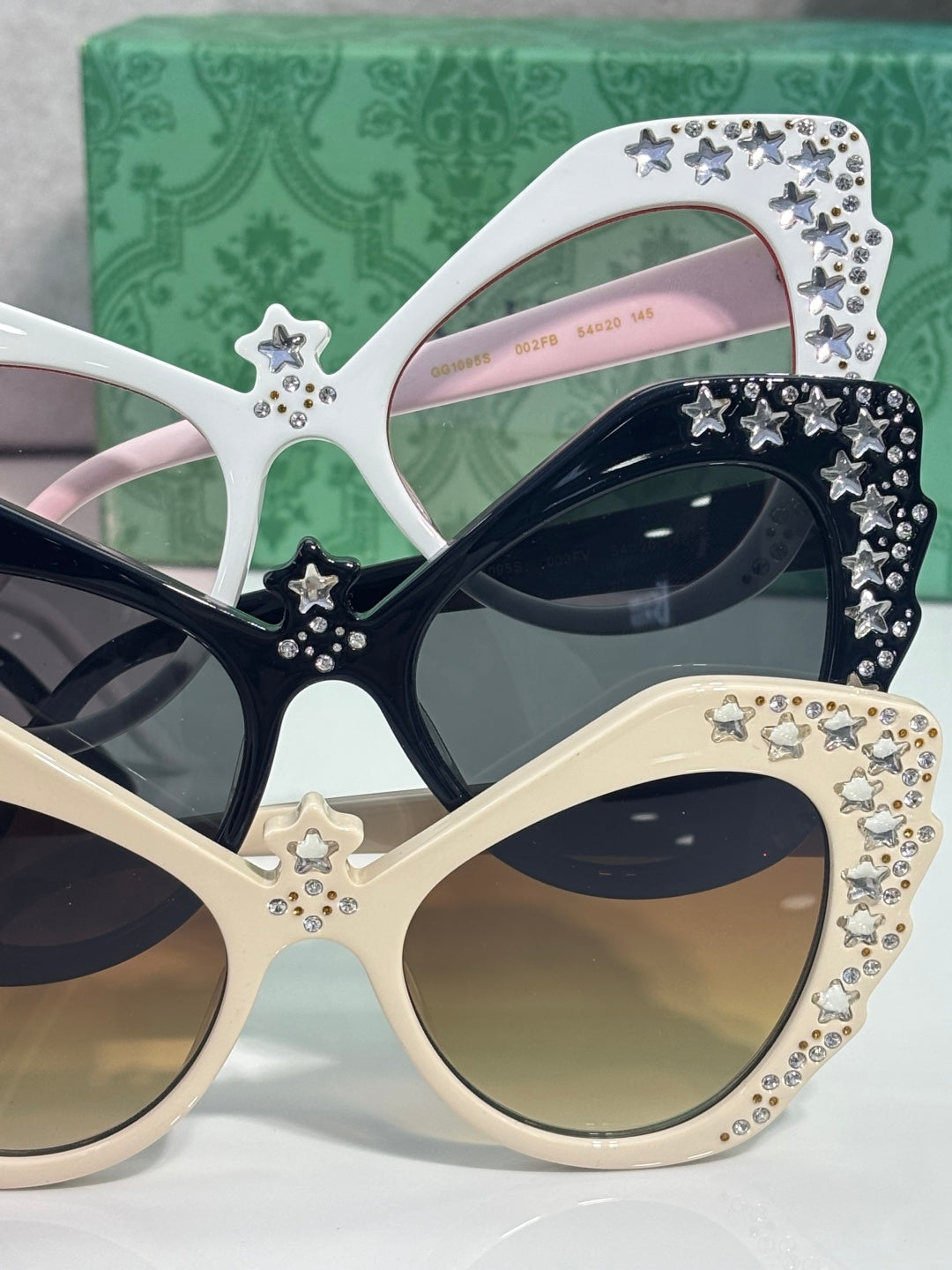 Gucci glasses with white cat-eye frames, rhinestone stars, and mixed dark and pink lenses.