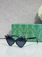 Black cat-eye sunglasses with studded temples, dark lenses; logo on arms