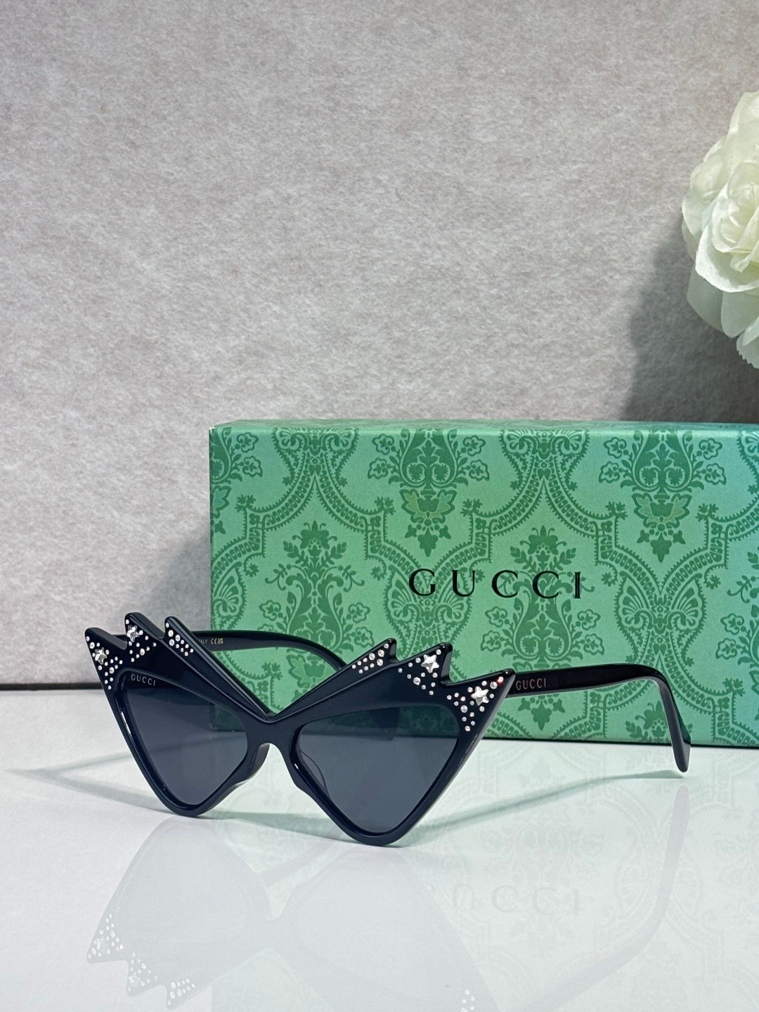 Black cat-eye sunglasses with studded temples, dark lenses; logo on arms