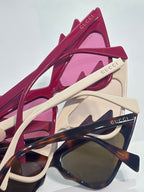 Pink cat-eye sunglasses with cream arms and rhinestone studs, tinted lenses