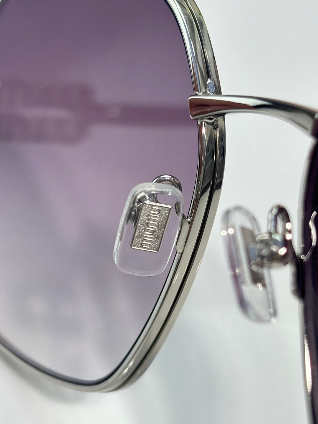 MiuMiu sunglasses close-up: gold rim and hinge with engraved logo detail