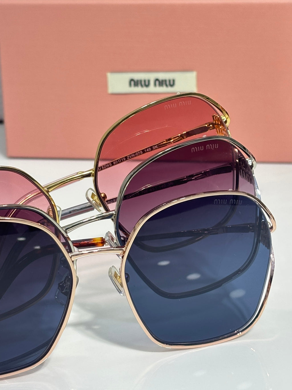 MiuMiu sunglasses pair, gold frames, pink and dark blue gradient lenses