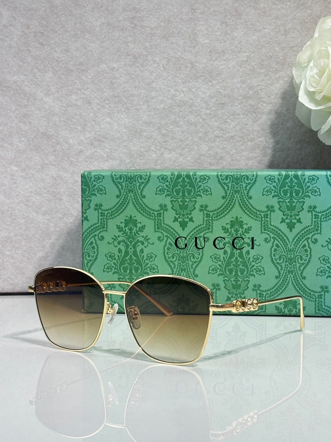 Gucci sunglasses with green-tinted lenses and gold-tone frame