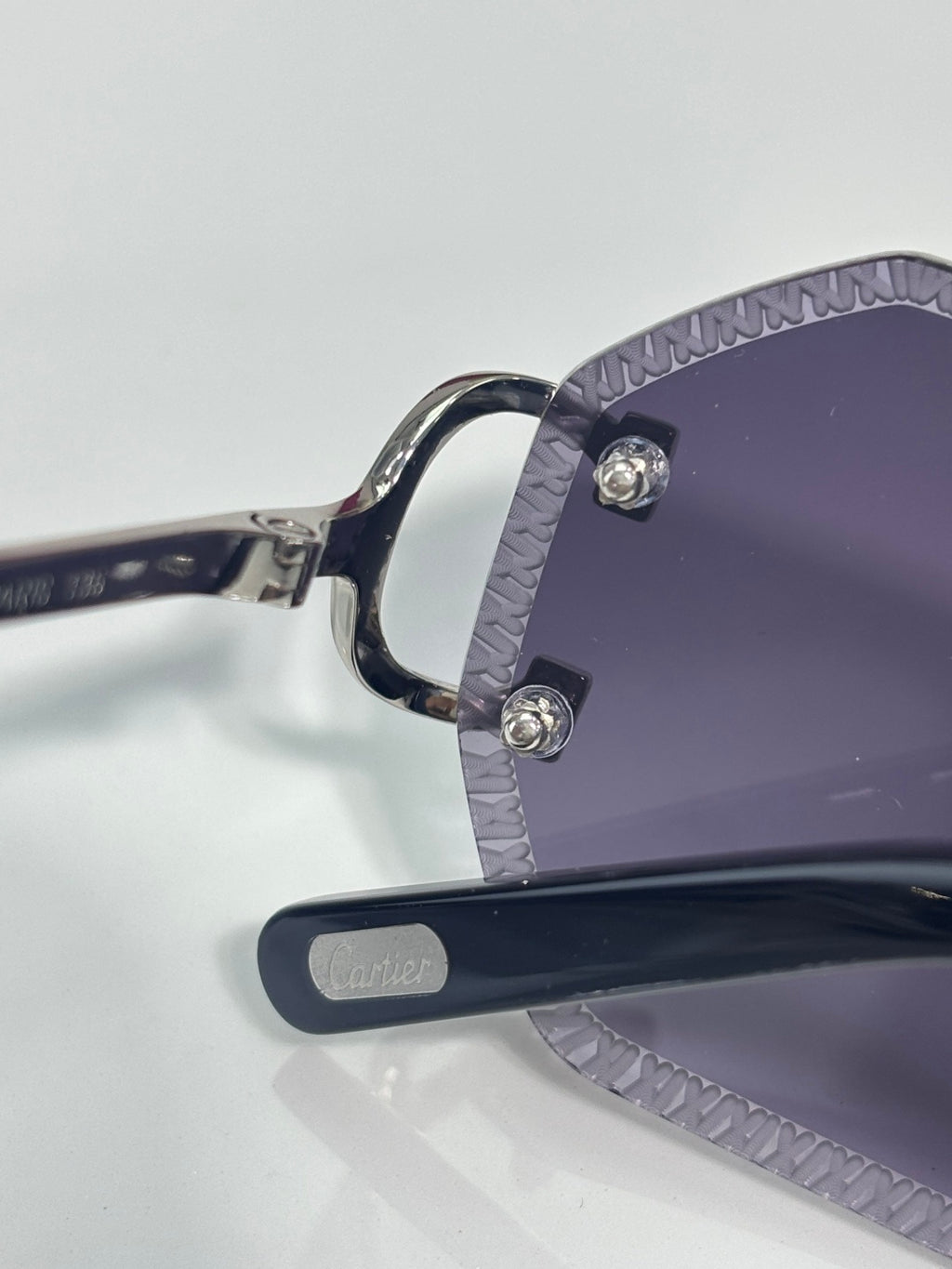 Cartier eyeglasses close-up of navy temple tip and purple lens front, metal screws visible
