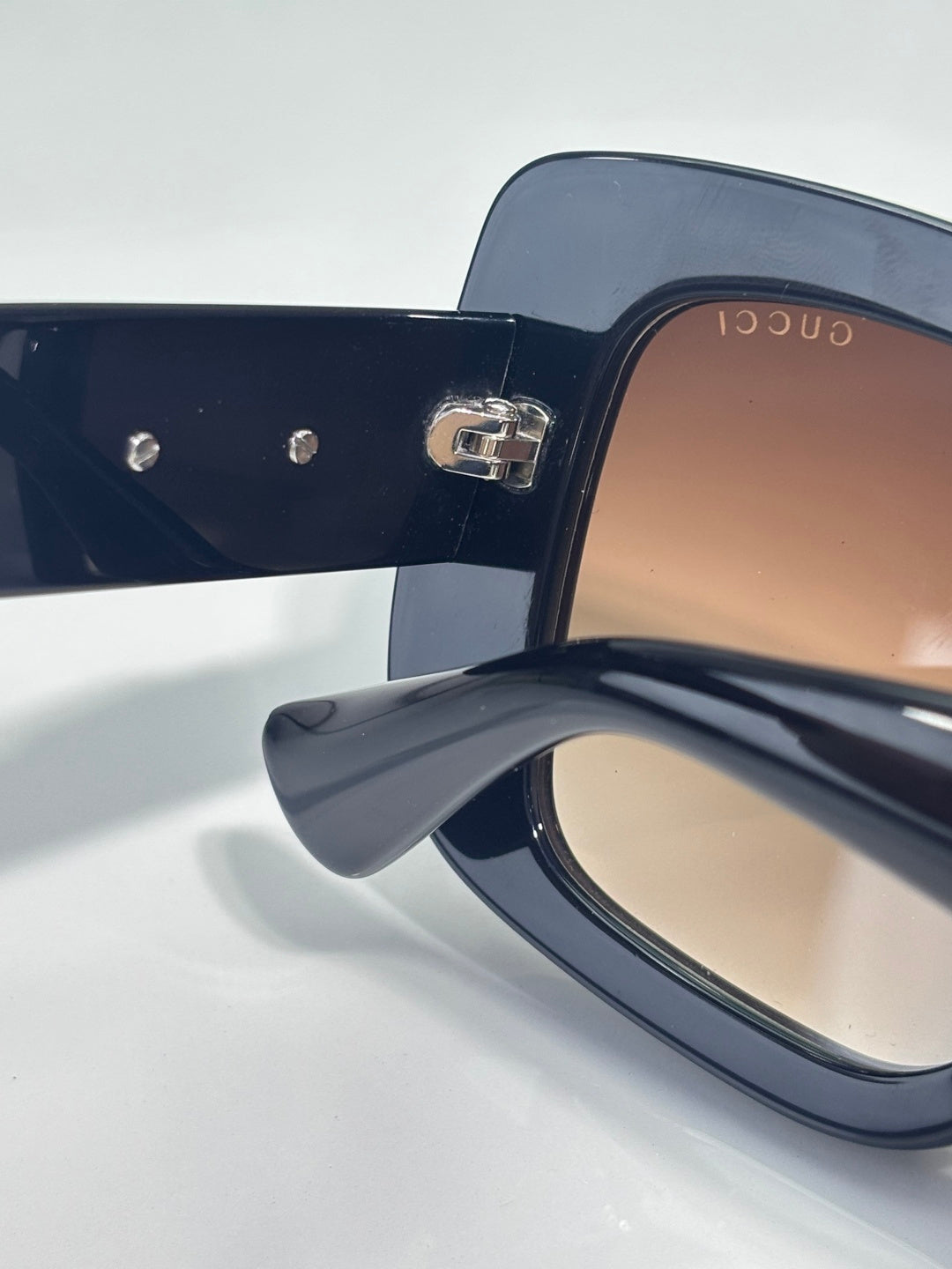 Gucci sunglasses close-up of dark blue frame with gold Gucci logo on temple