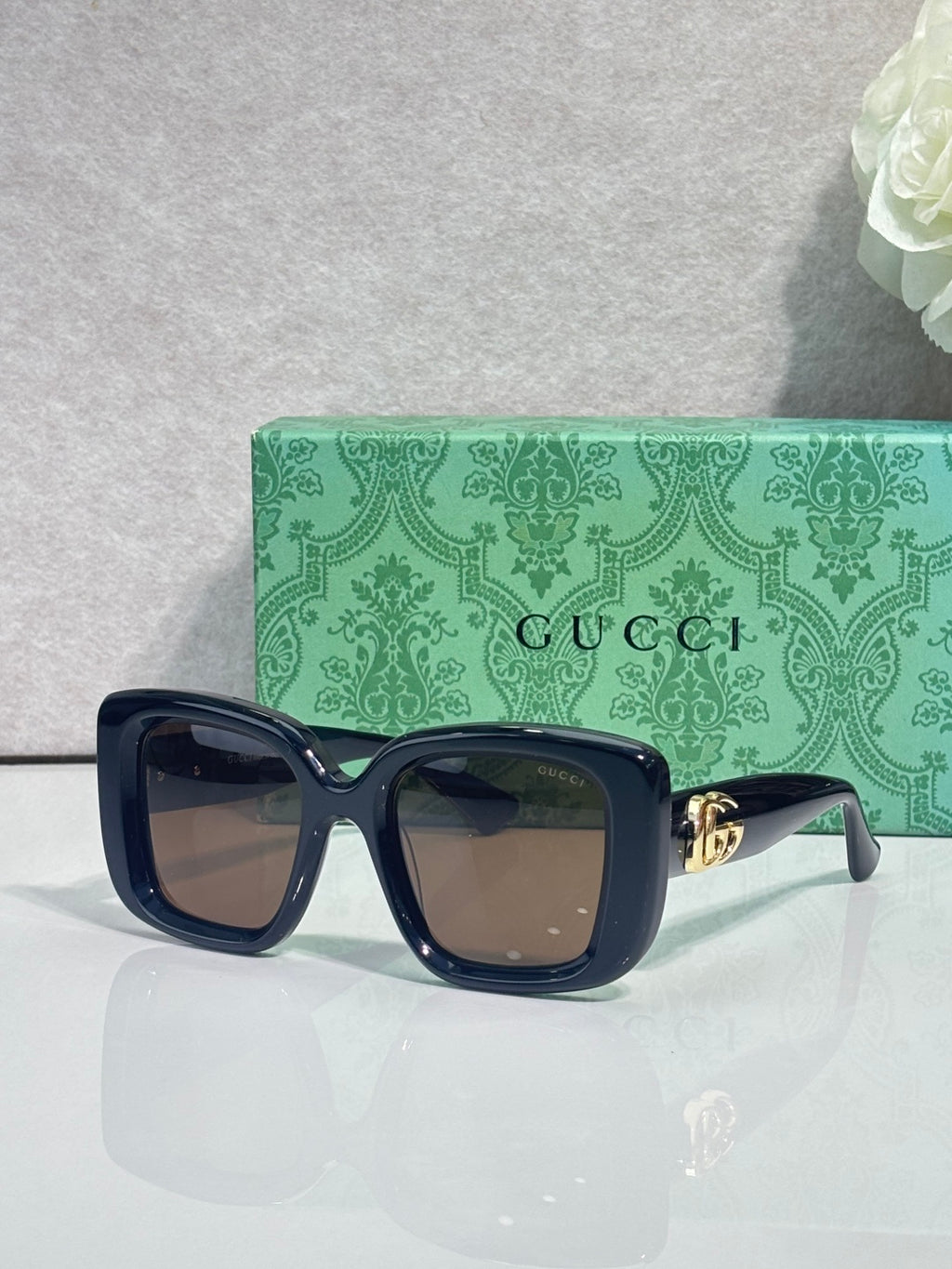 Gucci sunglasses with dark blue frames and tinted lenses, gold hinge detail