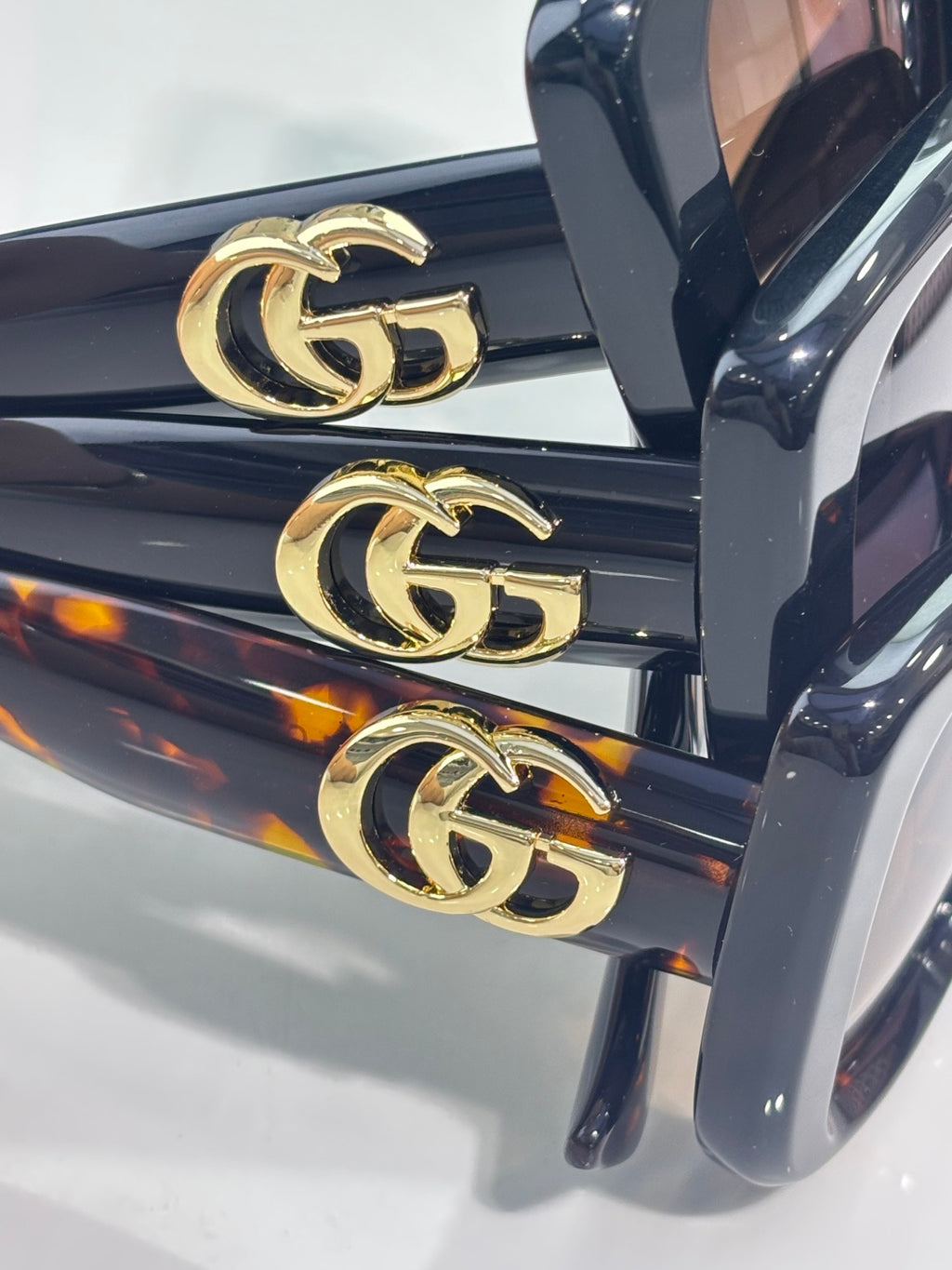 Gucci sunglasses close-up of gold GG logo hardware on dark blue frame
