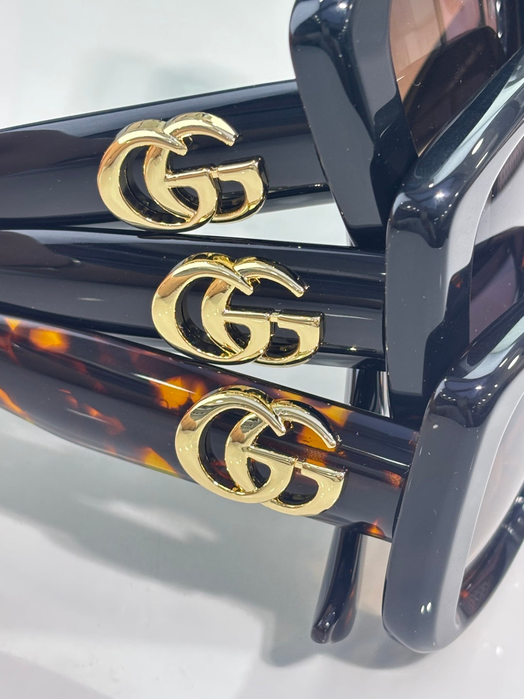 Gucci sunglasses close-up of gold GG logo hardware on dark blue frame