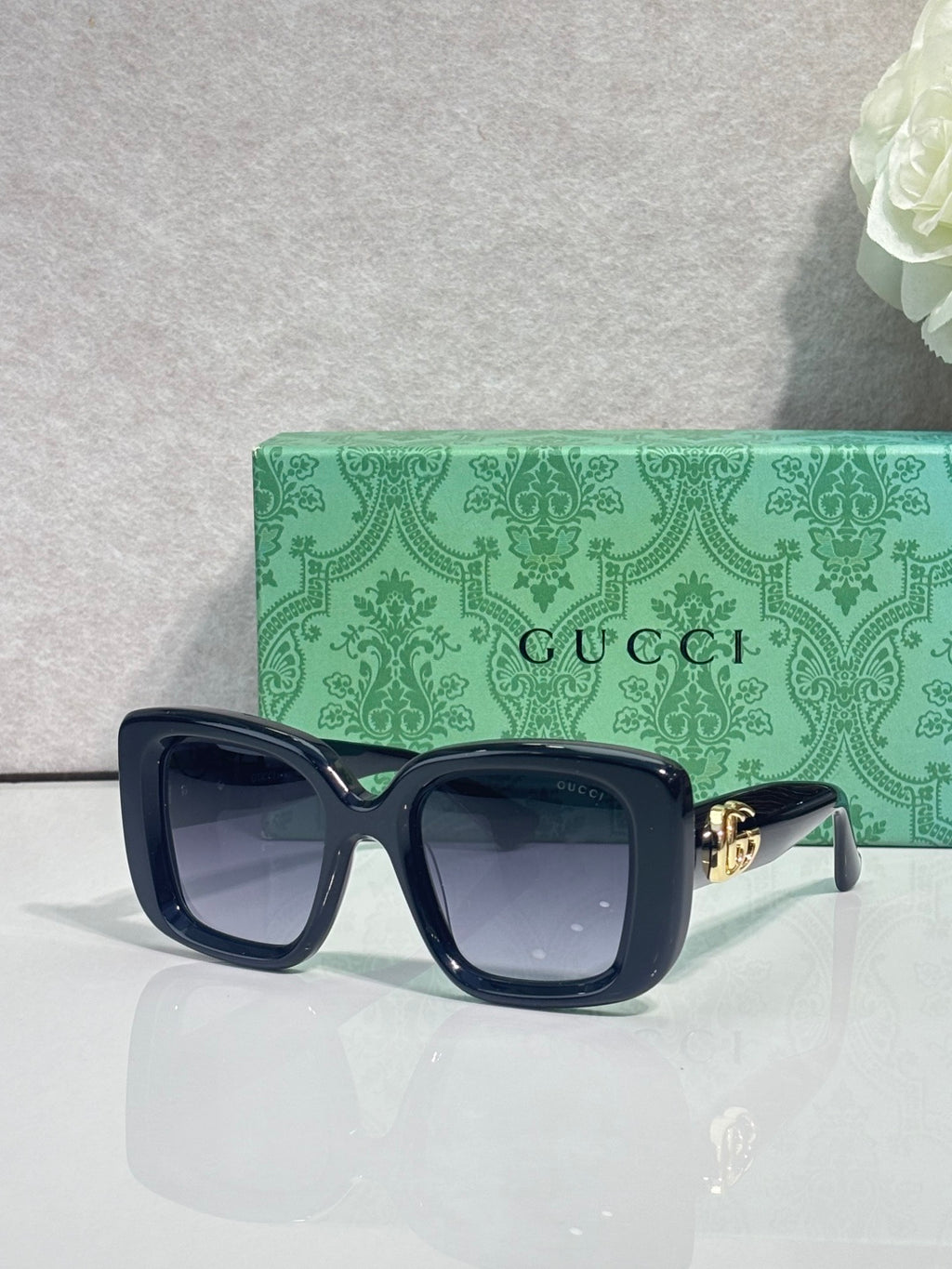Gucci sunglasses with dark blue frames and green-tinted rectangular lenses
