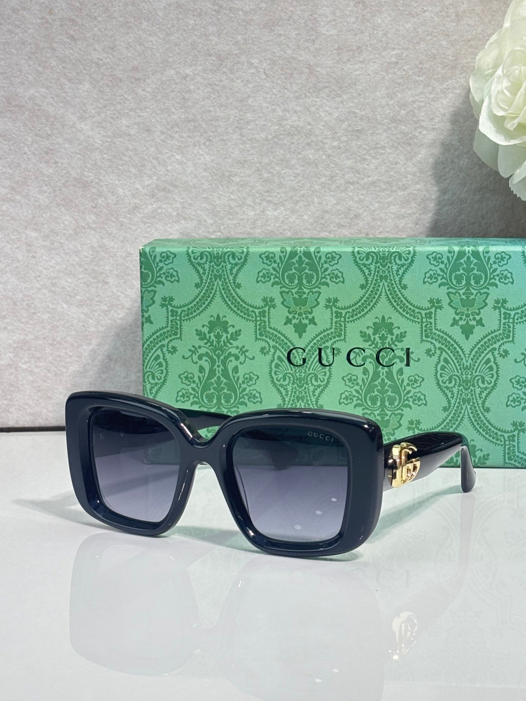Gucci sunglasses with dark blue frames and green-tinted rectangular lenses