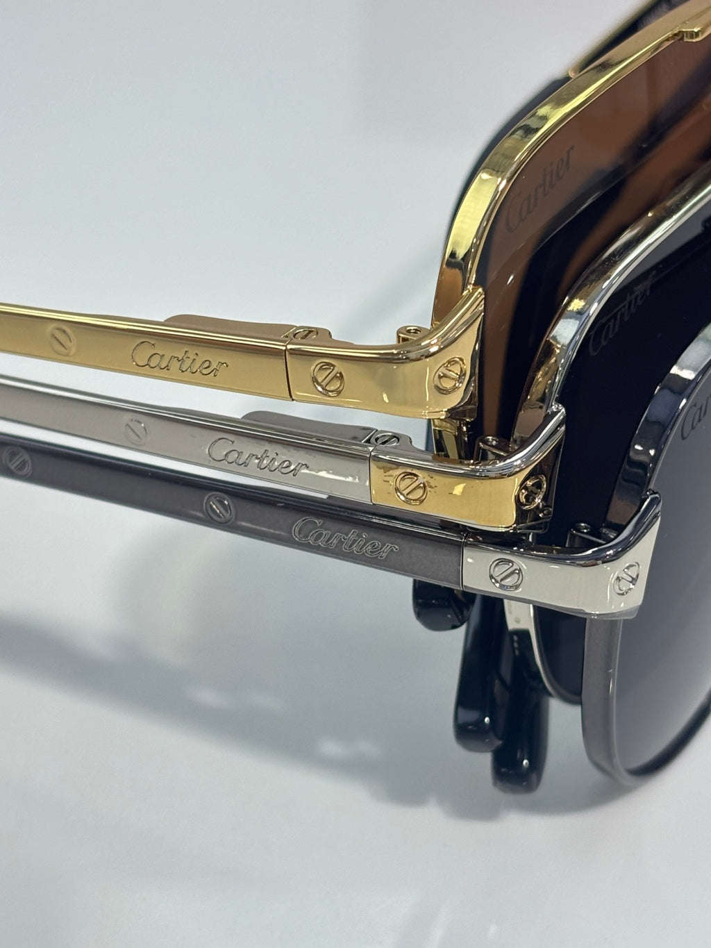 Cartier sunglasses detail, gold and silver arms with engraved logo, dark lenses