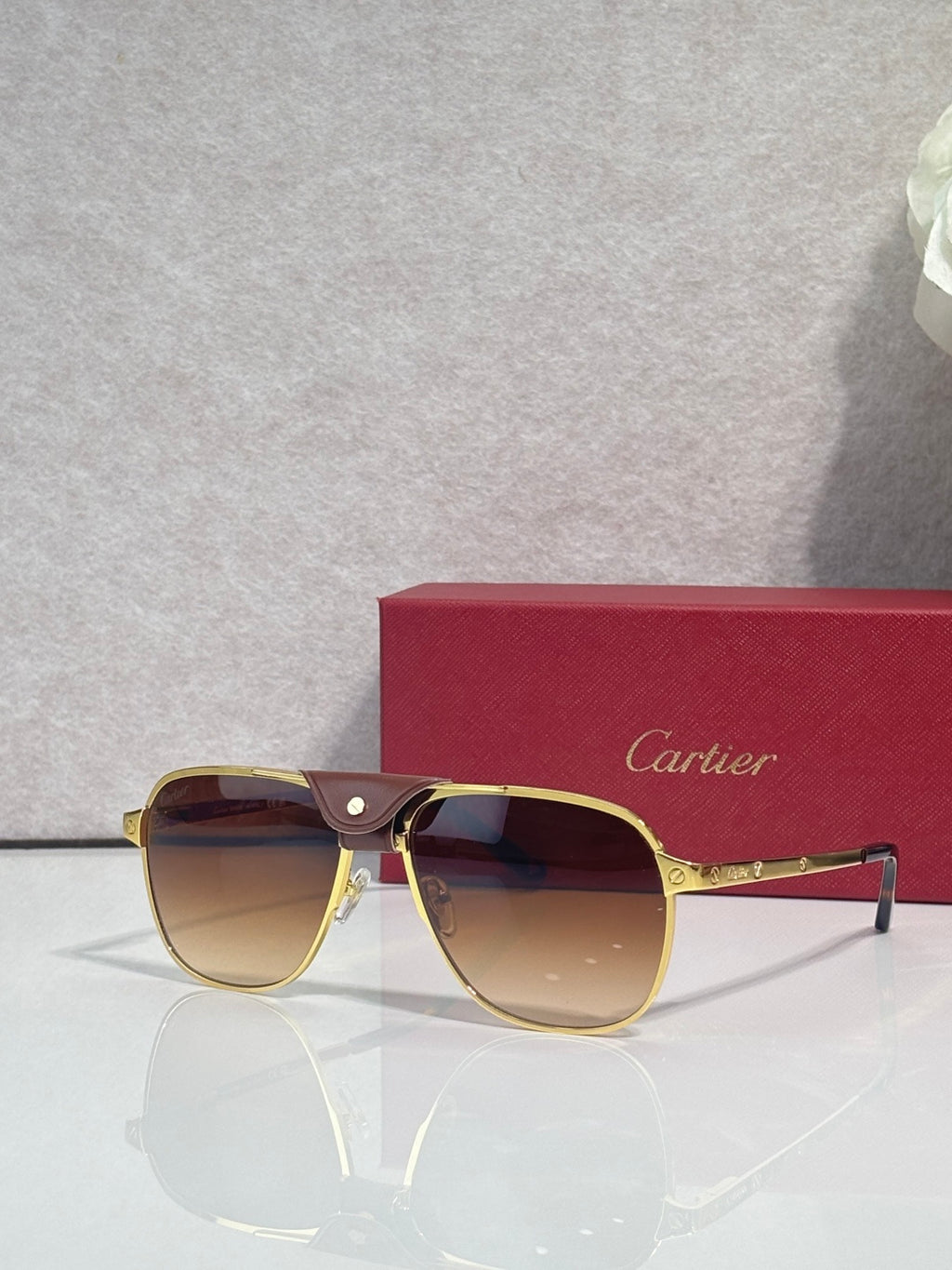 Sunglasses with gold frames and amber tinted lenses, side temple detail