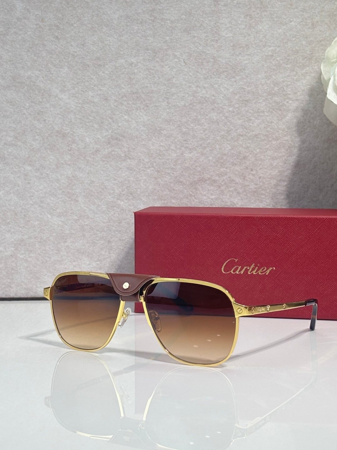 Sunglasses with gold frames and amber tinted lenses, side temple detail