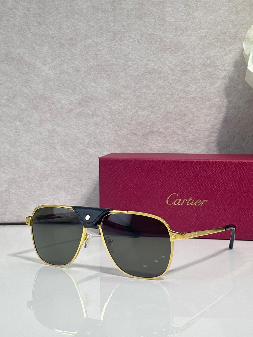 Sunglasses with gold frames and dark tinted lenses, angled front view