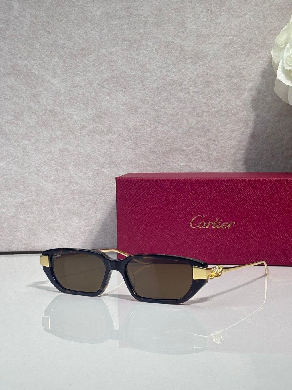 Cartier eyeglasses with dark blue frames, brown lenses, and gold-tone cat logo detail