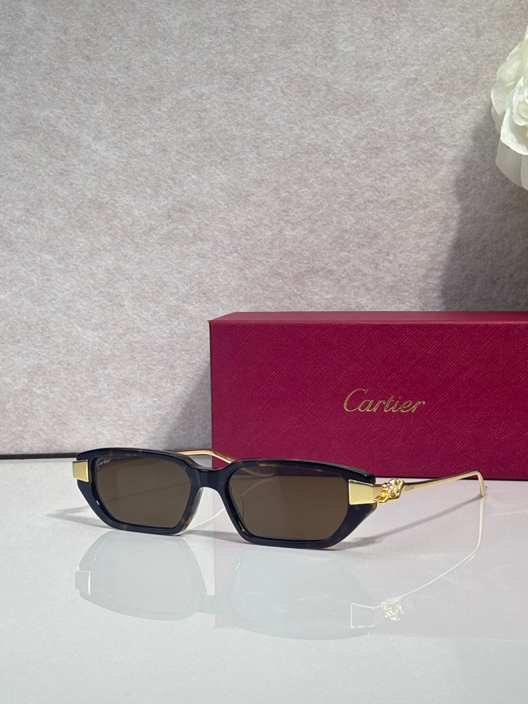 Cartier eyeglasses with dark blue frames, brown lenses, and gold-tone cat logo detail