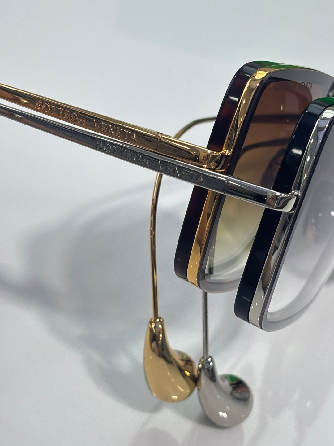Side close-up of sunglasses with gold bar detailing and dark navy acetate frames.