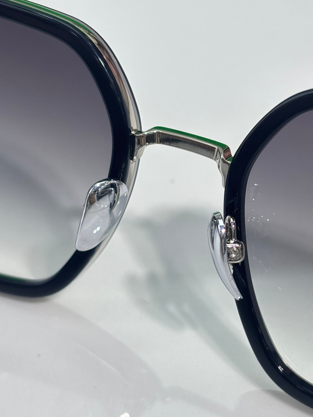 Close-up of round-edged sunglasses frame with dark navy acetate and gold metal hardware.