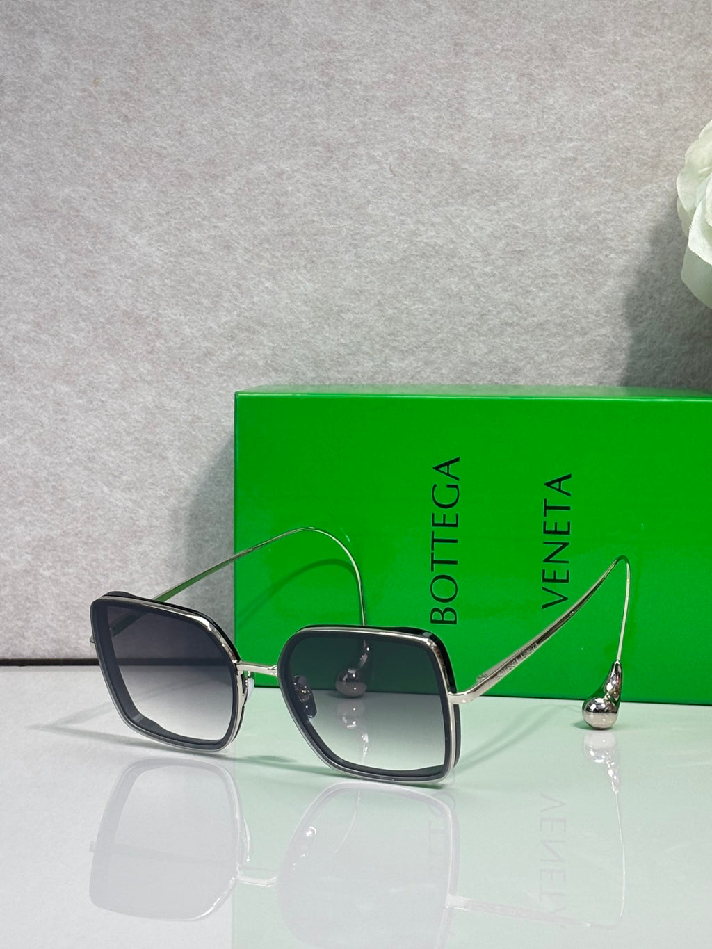Square sunglasses with dark navy/black frame and light gray-tinted lenses, gold metal accents.