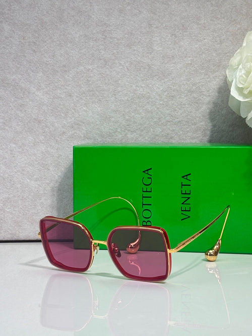 Square sunglasses with burgundy frame and rose-tinted lenses, gold metal accents.