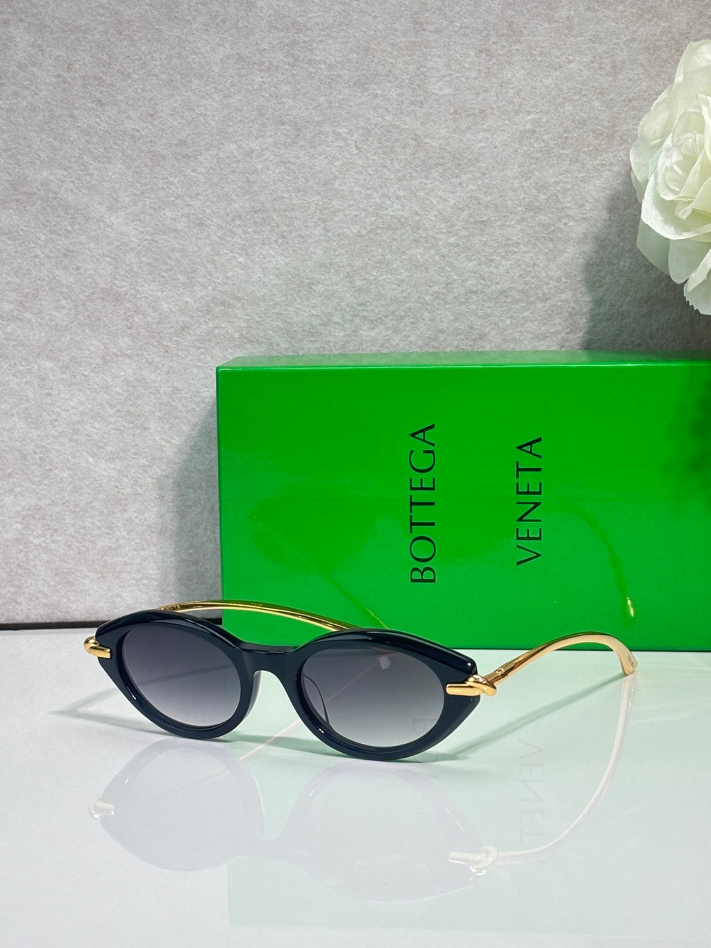 Bottega Veneta sunglasses with dark frames and gold-tone temples, dark lenses