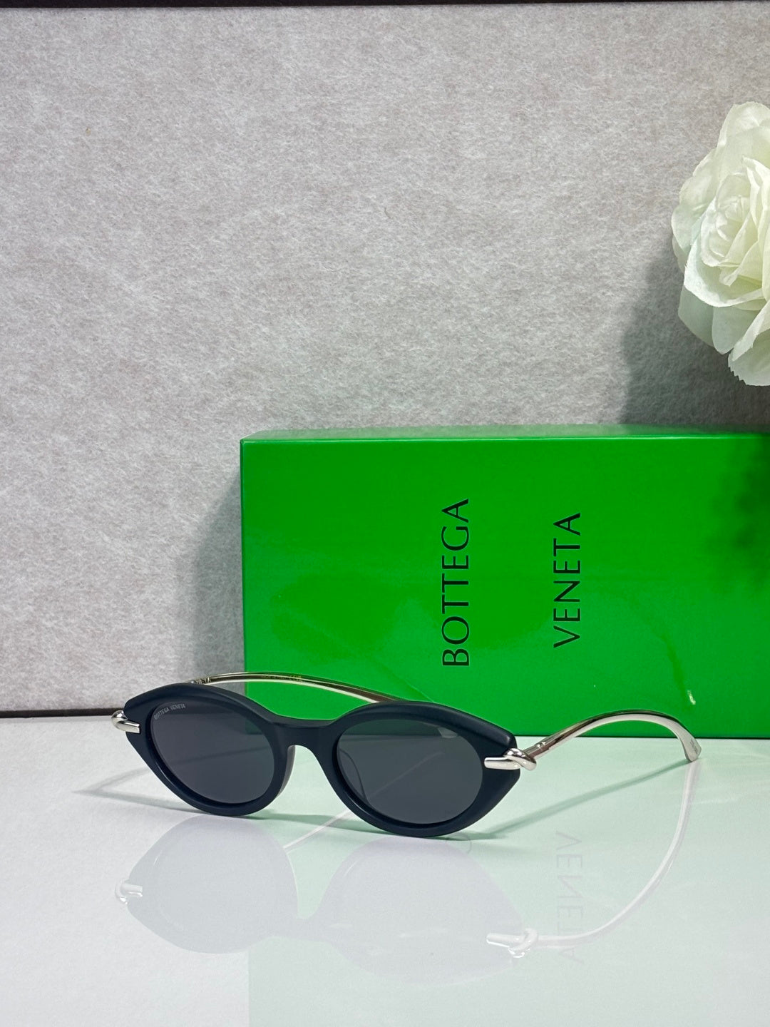 Bottega Veneta sunglasses with dark frames and gold-tone temples, dark lenses