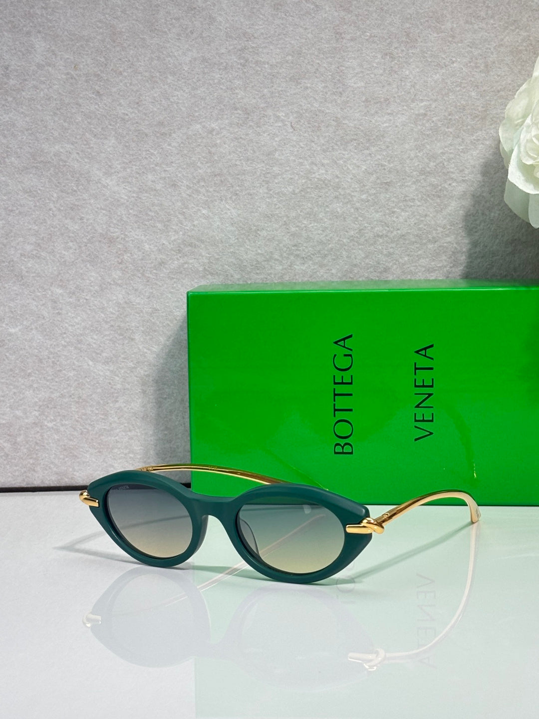 Bottega Veneta sunglasses with green frames and gold-tone temples, dark lenses