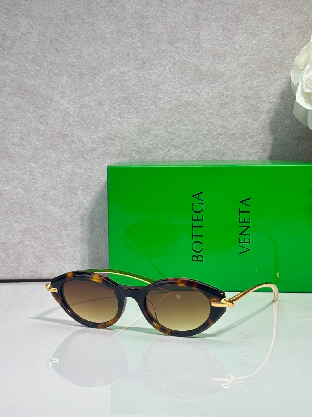 Bottega Veneta sunglasses with dark frames and gold-tone temples, brown lenses