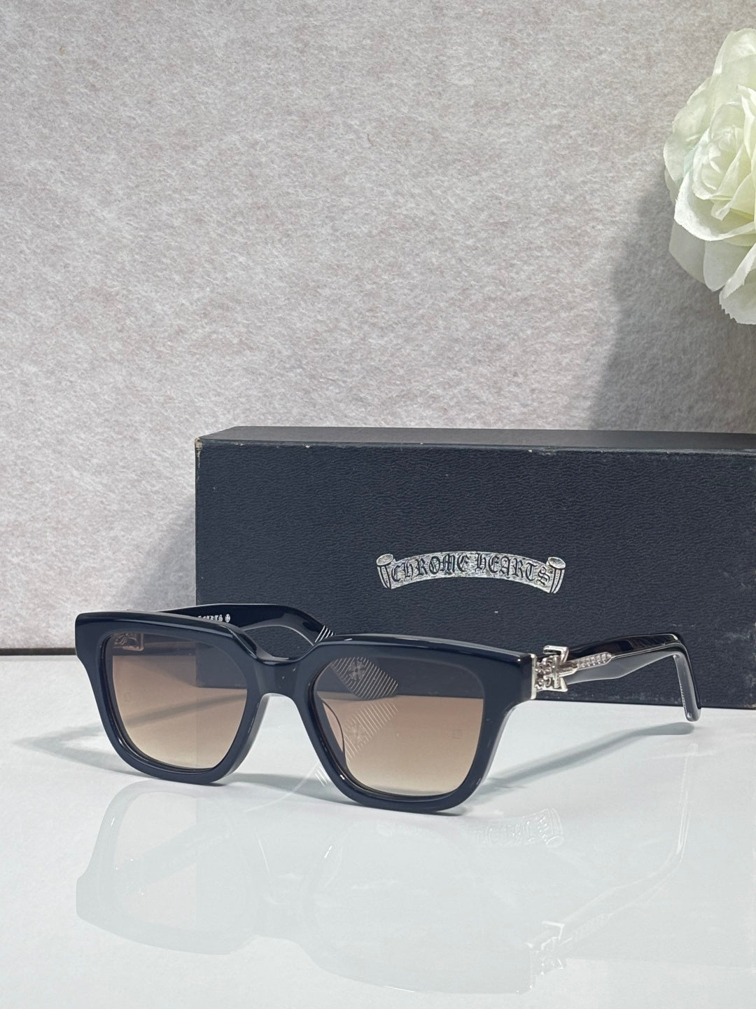 Chrome glasses with dark navy frames and clear lenses, front on display case