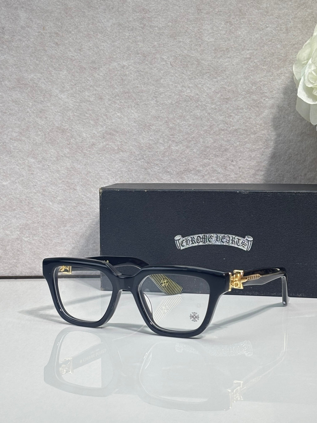 Black full-rim eyeglasses with clear lenses and gold-tone detail on the arm