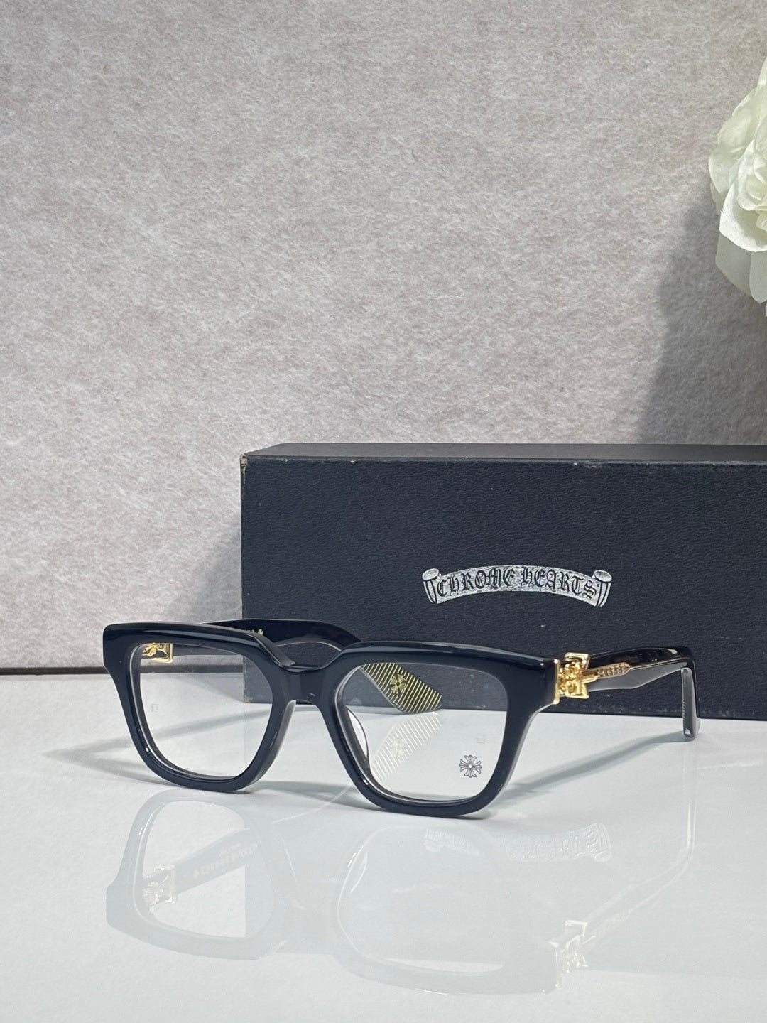 Black full-rim eyeglasses with clear lenses and gold-tone detail on the arm