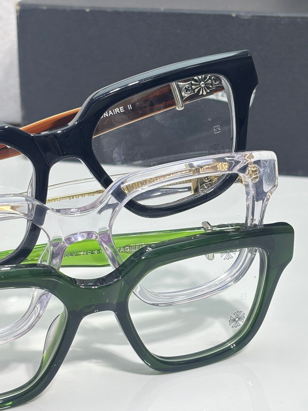 Close-up of eyeglass frames with clear lenses, green and navy accents