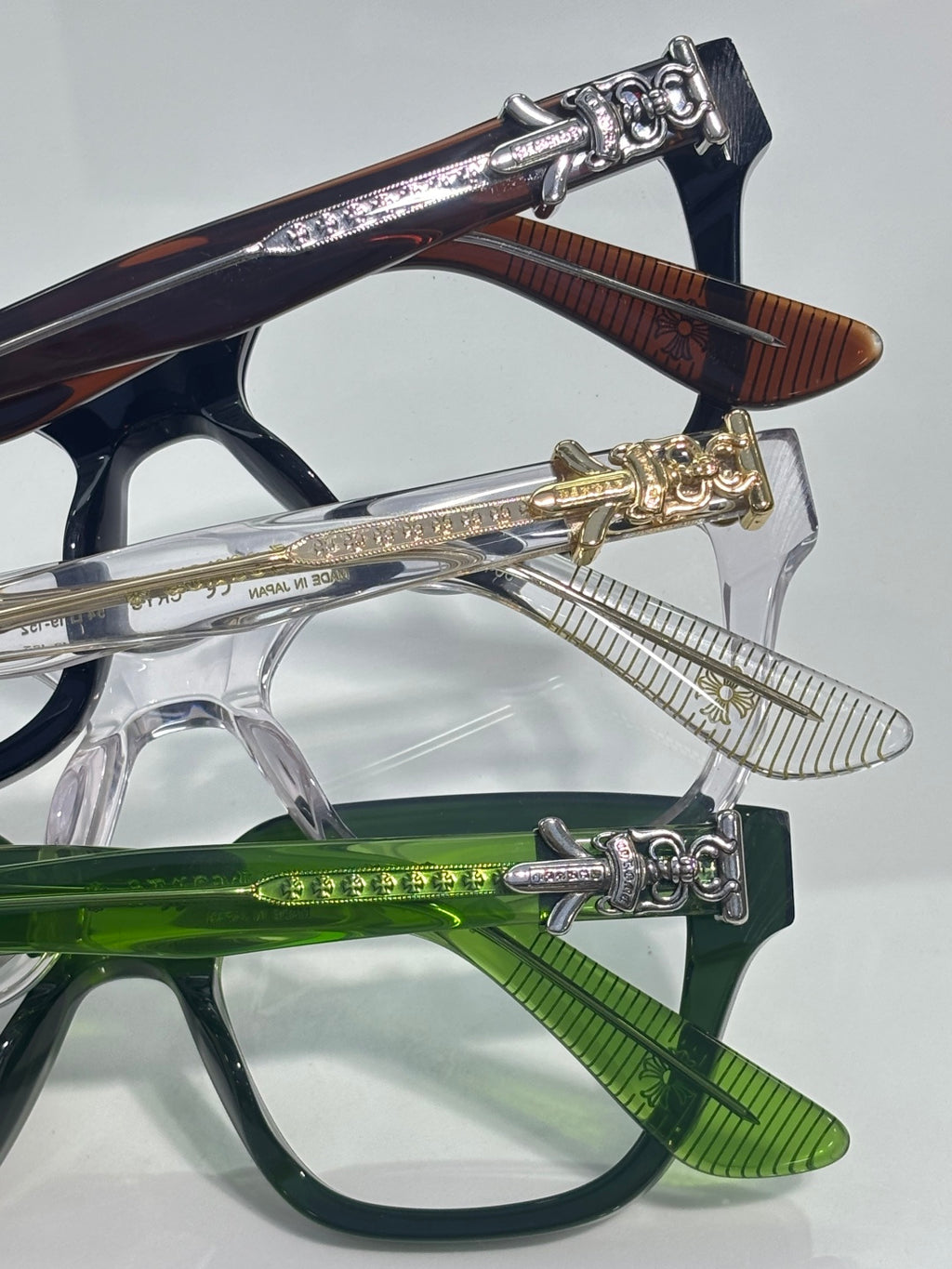 Close-up of stacked eyeglasses with blue, green, and silver frames and clear lenses